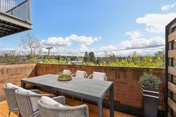 A table with chairs on a balcony with a view of the sky.